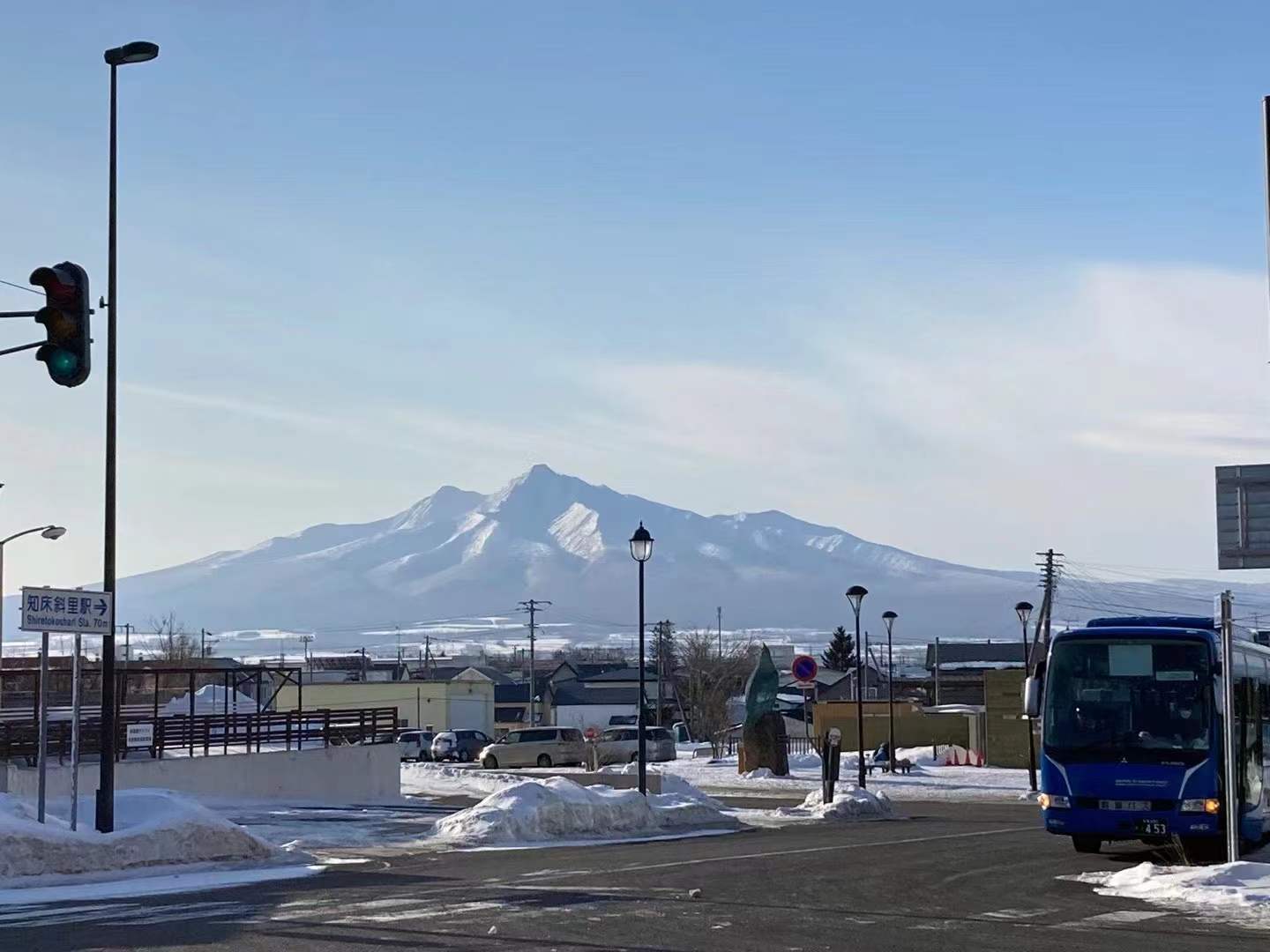 A snow-covered mountain seen beyond a railway platform in Japan